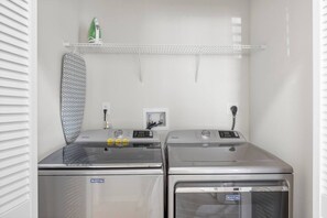 A laundry room with two Maytag washing machines, a drying rack, and a green iron on a shelf. - Relaxing 2BR Stay | Pool, Gym & Free Parking (Largo)