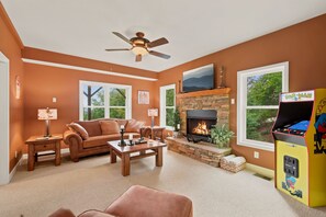 A living room with a fireplace, a couch, a coffee table, and a Pac-Man arcade machine. - Cedar Sunset - Big Views, Two Fireplaces, 4BR on Beech Mountain (Beech Mountain)