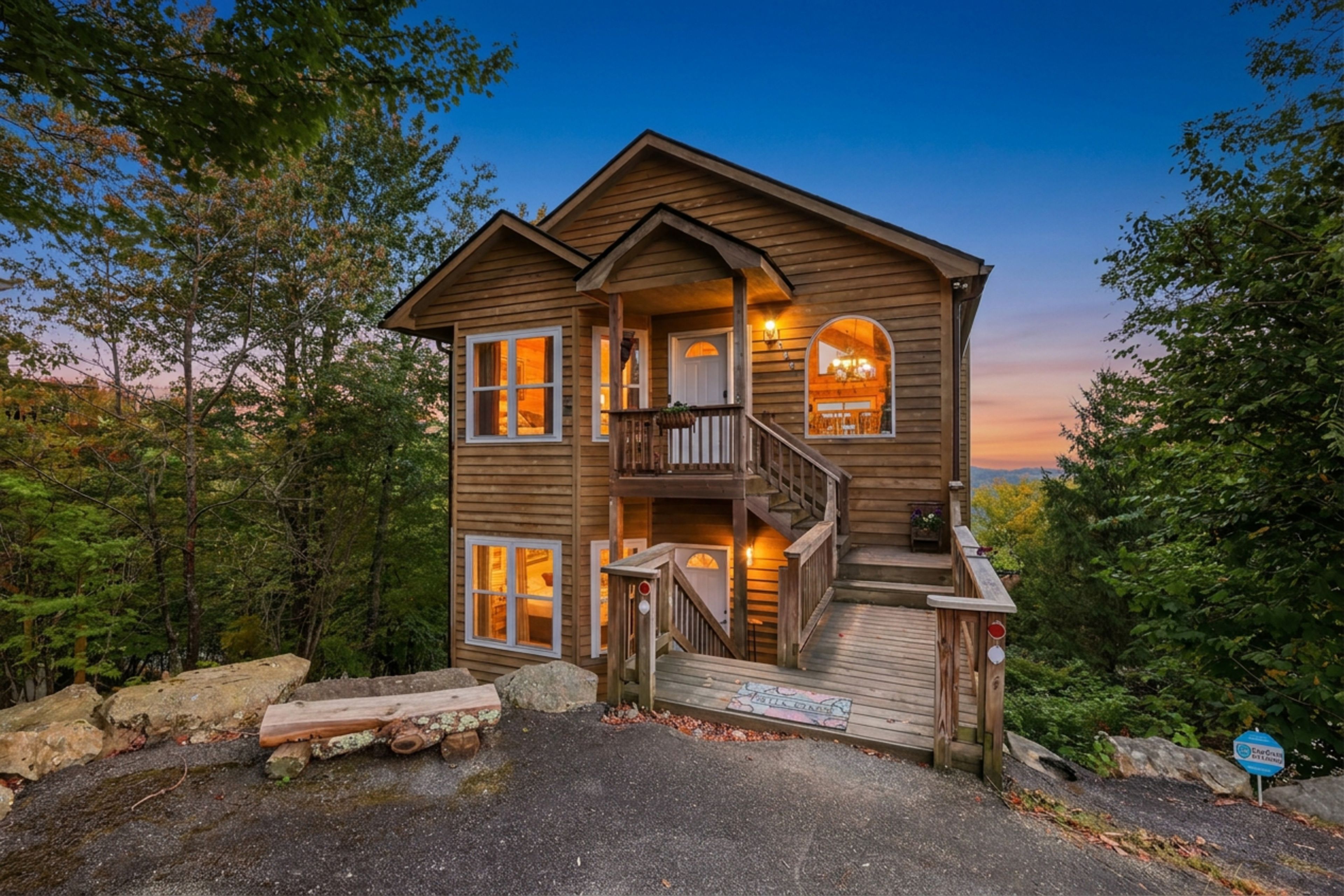 A two-story wooden cabin with a balcony, a staircase, and a porch.