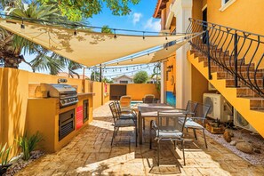 Eine Außenpatio mit Grill, Esstisch, Stühlen und einer Treppe.