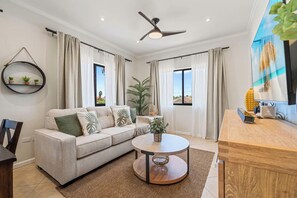 Ein modernes Wohnzimmer mit einer Couch, einem runden Couchtisch und einem Deckenventilator.