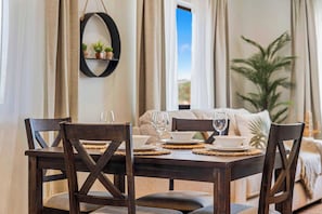 A dining area with a table set for two, chairs, and a view of the outdoors. - Villa Sail Away | Private Jacuzzi & Courtyard (Noord)