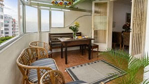 Un balcon agrémenté de meubles en osier, d’une table à manger et d’une plante en pot.