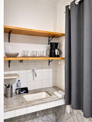 A bathroom with a sink, a coffee maker, and a shelf with cups and a bowl. - Hospedagem Rio Lapa 3 (Rio de Janeiro)