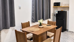 A dining area with a wooden table and chairs, a small potted plant, and a kitchen area with a microwave and refrigerator. - Hospedagem Rio Lapa 3 (Rio de Janeiro)