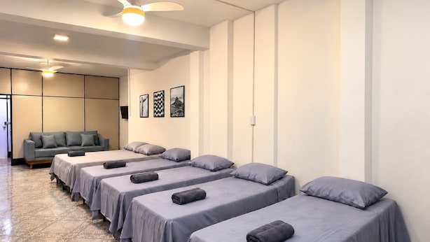 A hotel room with four single beds, a sofa, and a ceiling fan. - Hospedagem Rio Lapa 3 (Rio de Janeiro)