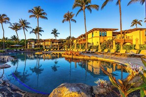 Ein Resort mit Pool, Palmen und einem Gebäude mit mehreren Balkonen.