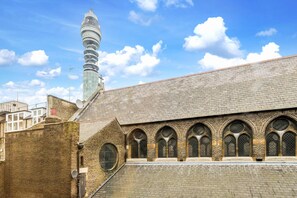 A building with a brick facade, multiple arched windows, and a distinctive tower with a spiral design. - Cosy 1-bed - Fitzrovia - Sleeps 3 (London)