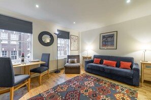 A modern living room with a sofa, chairs, a dining table, and a patterned rug. - Cosy 1-bed - Fitzrovia - Sleeps 3 (London)