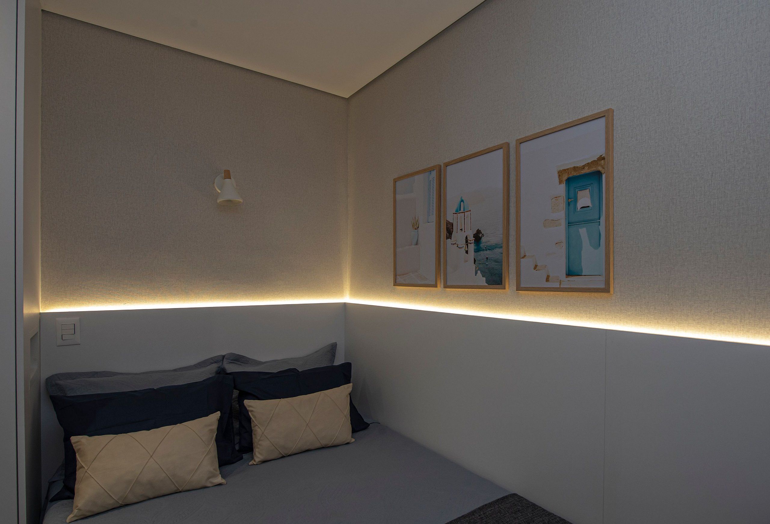 Un dormitorio ordenado con cama, almohadas y cuadros en la pared.
