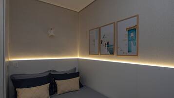 Un dormitorio ordenado con cama, almohadas y cuadros en la pared.
