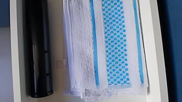 A drawer with a black cylindrical object, a white object with blue patterns, and a blue patterned object.
