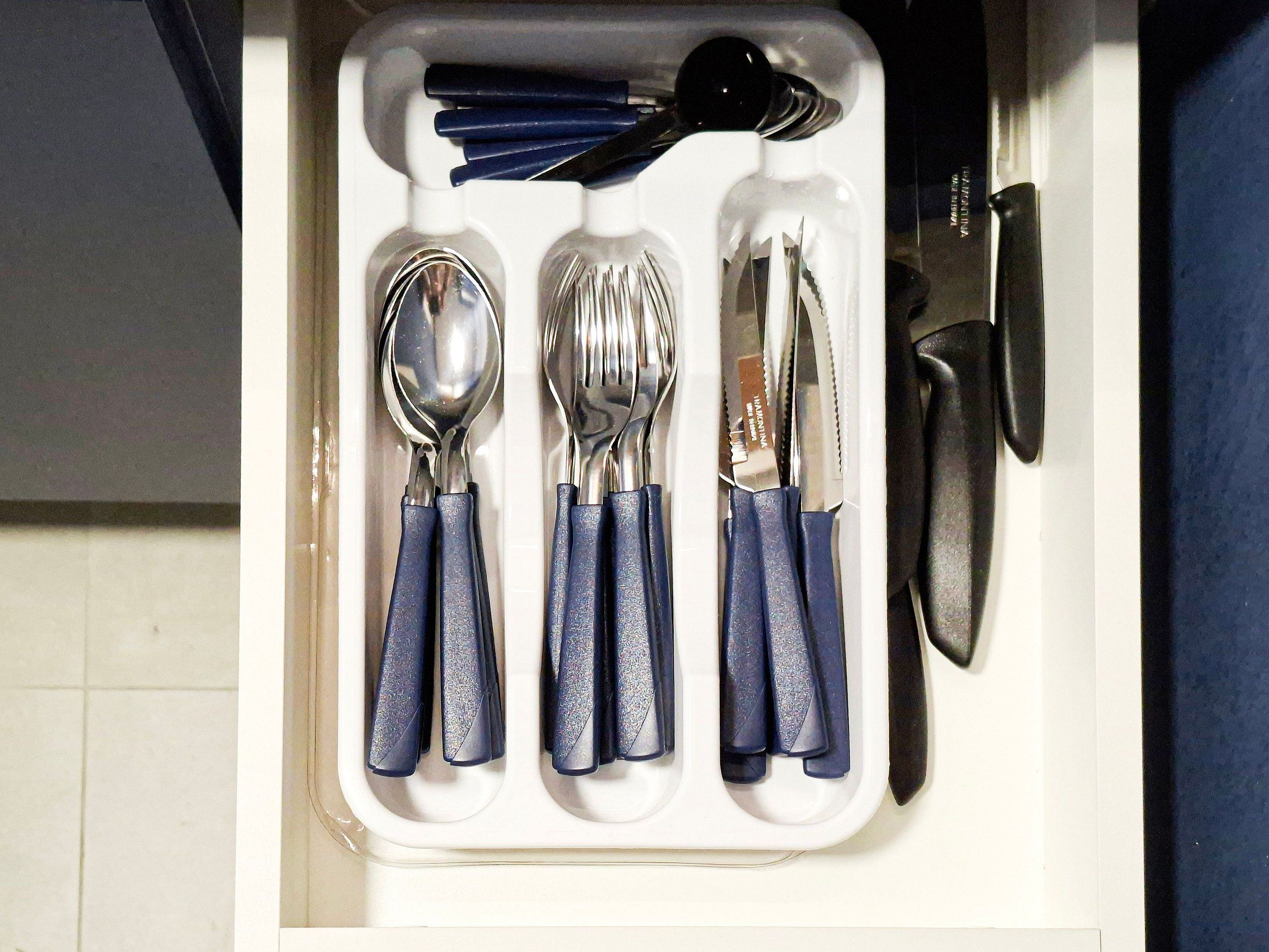A drawer containing a set of utensils including a spoon, fork, knife, and chopsticks.