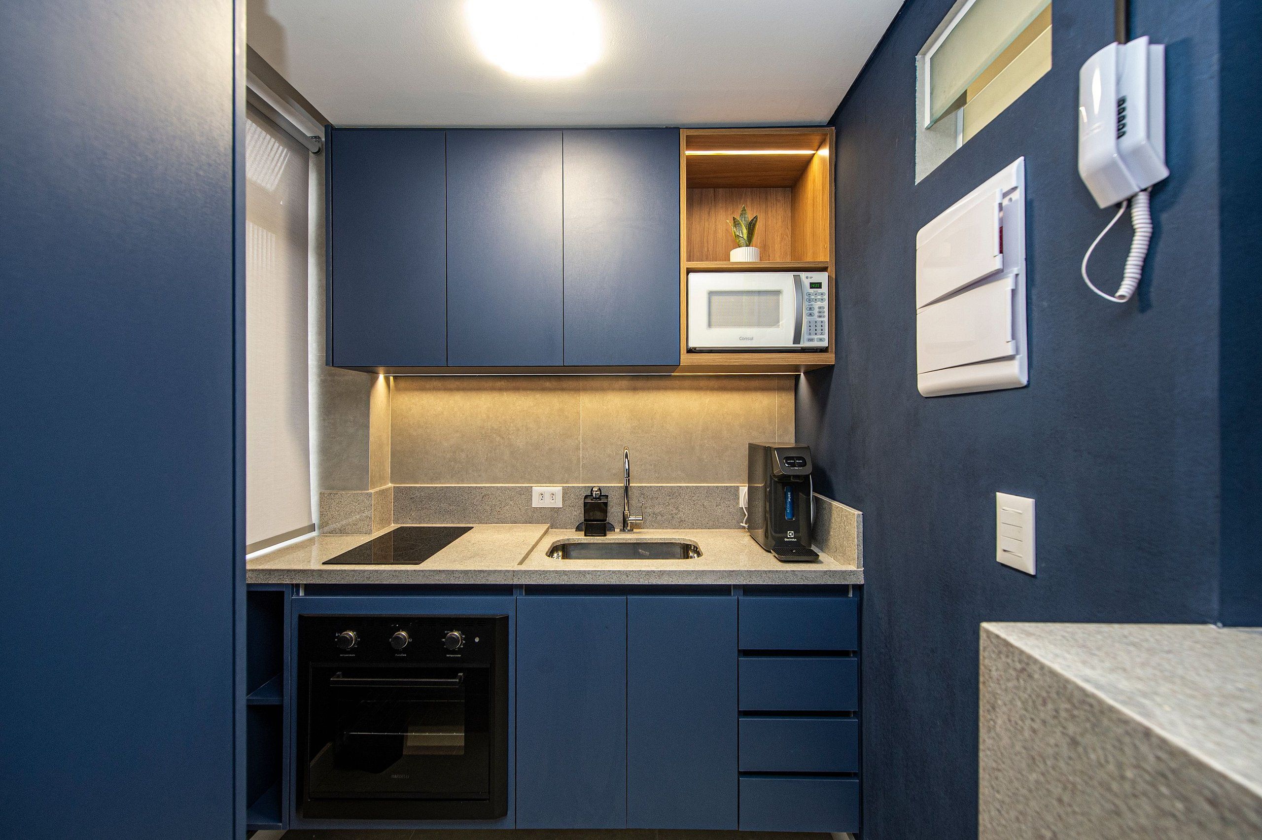 A compact kitchen with a microwave, coffee maker, and oven.