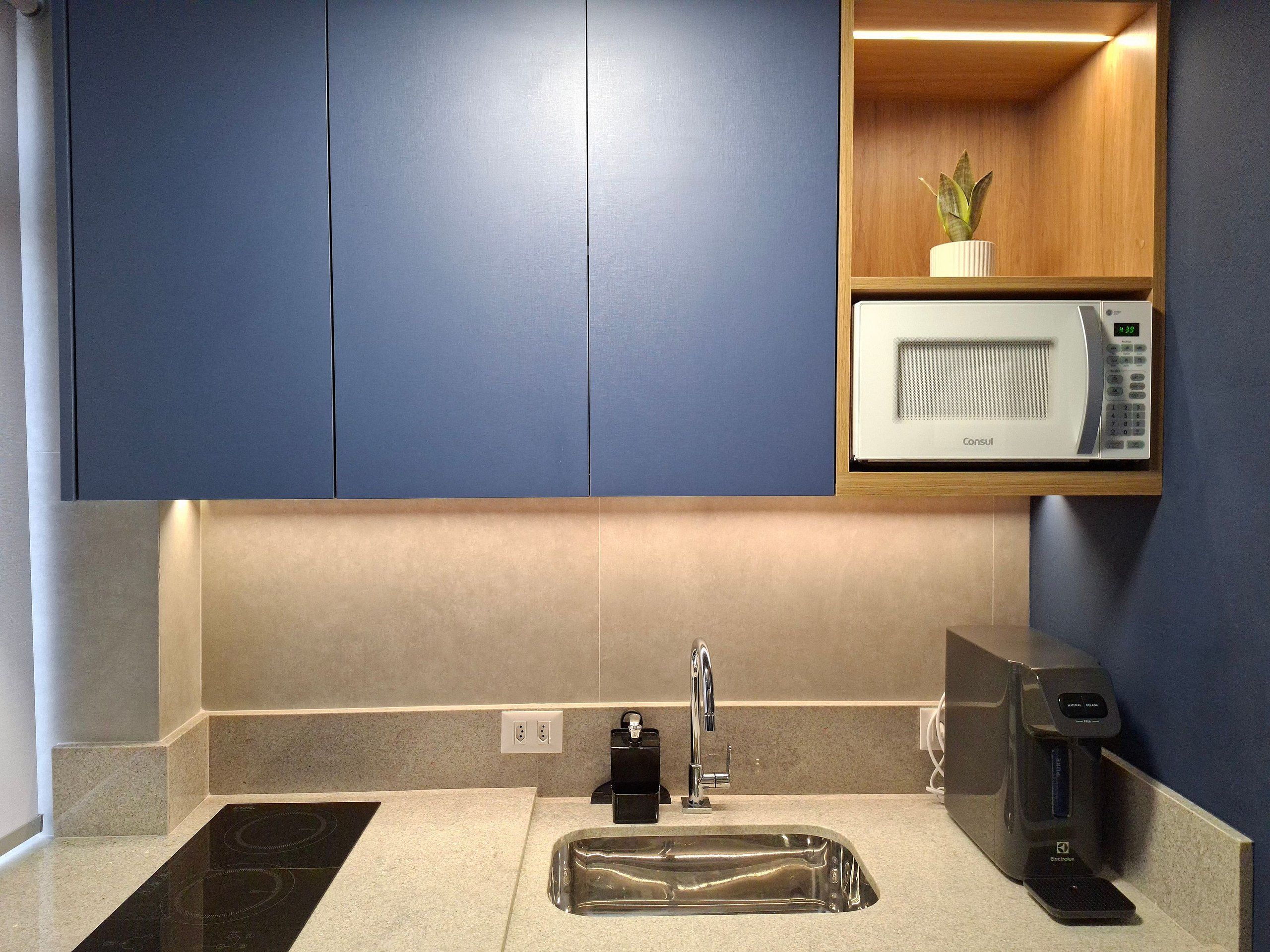 A modern kitchen with a built-in microwave, a coffee machine, and a sink.