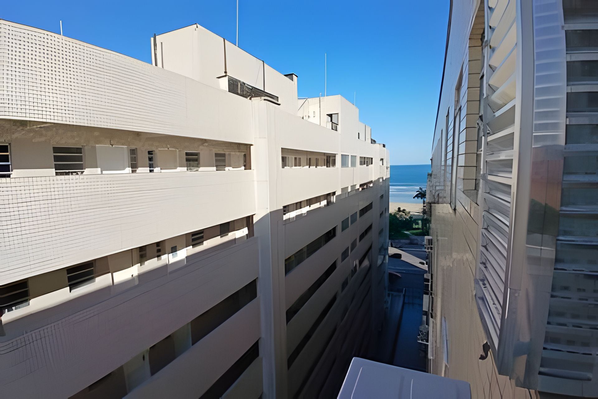 A high-rise building with multiple balconies overlooking a beach.