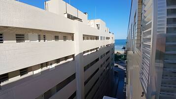 A high-rise building with multiple balconies overlooking a beach.