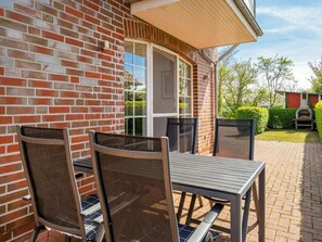 Eine Terrasse mit Tisch und Stühlen, eine Backsteinmauer und eine hölzerne Pergola.
