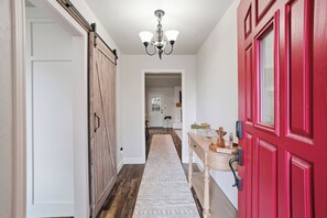 Ein Flur mit einer Holztür, einer roter Tür, einer weißen Wand und einer Deckenleuchte.
