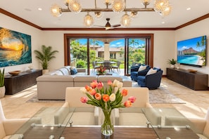 A modern living room with a glass coffee table, sofas, a dining area, and a large TV screen. - Wailea Beach | 2 Oceanfront Villas, Sleeps 14 | Car Incl. w/ 6+ Nights | ML-4274 by KBM (Wailea)