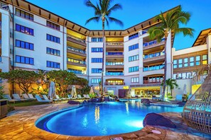 Ein Hotel mit Schwimmbad, mehreren Balkonen und Palmen.