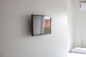 A wall-mounted refrigerator in a room with a white wall and a white pillow on a white surface.