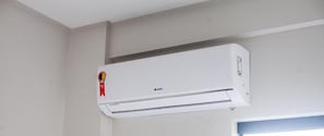Un aire acondicionado blanco, fijado a la pared, con una etiqueta roja en el lado izquierdo.