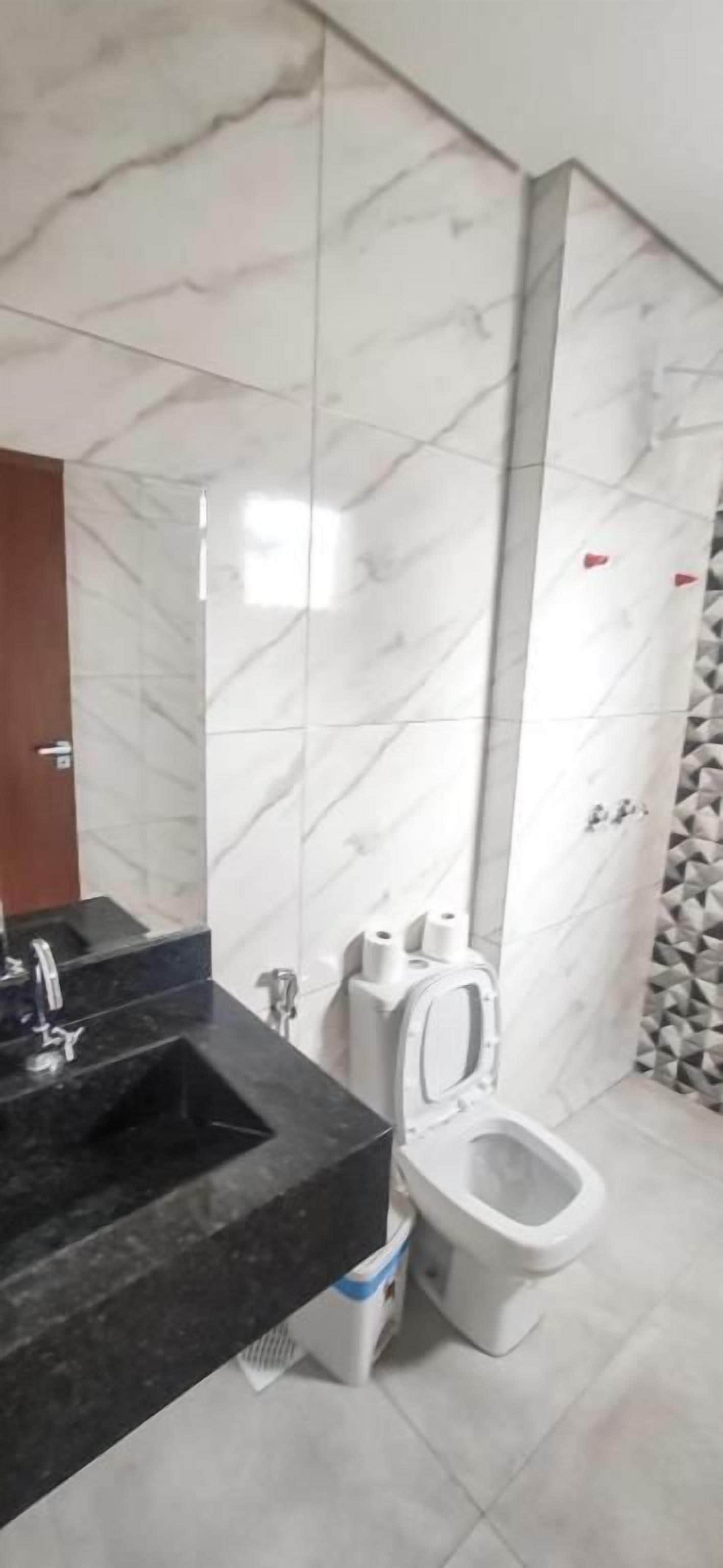 A bathroom with a marble wall, a black sink, and a toilet.