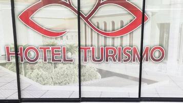 A hotel entrance with a logo and name 'HOTEL TURISMO' prominently displayed.