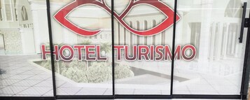 A hotel entrance with a logo and name 'HOTEL TURISMO' prominently displayed.