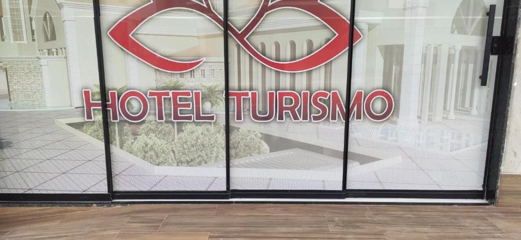 A hotel entrance with a glass door featuring the hotel's name 'HOTEL TURISMO' and a stylized logo.
