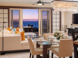 A modern living room with a sofa, dining table, and chairs, a balcony with a view of the sea, and a ceiling fan. - Wailea Beach | 2 Oceanfront Villas, Sleeps 14 | Car Incl. w/ 6+ Nights | ML-4280 by KBM (Wailea)
