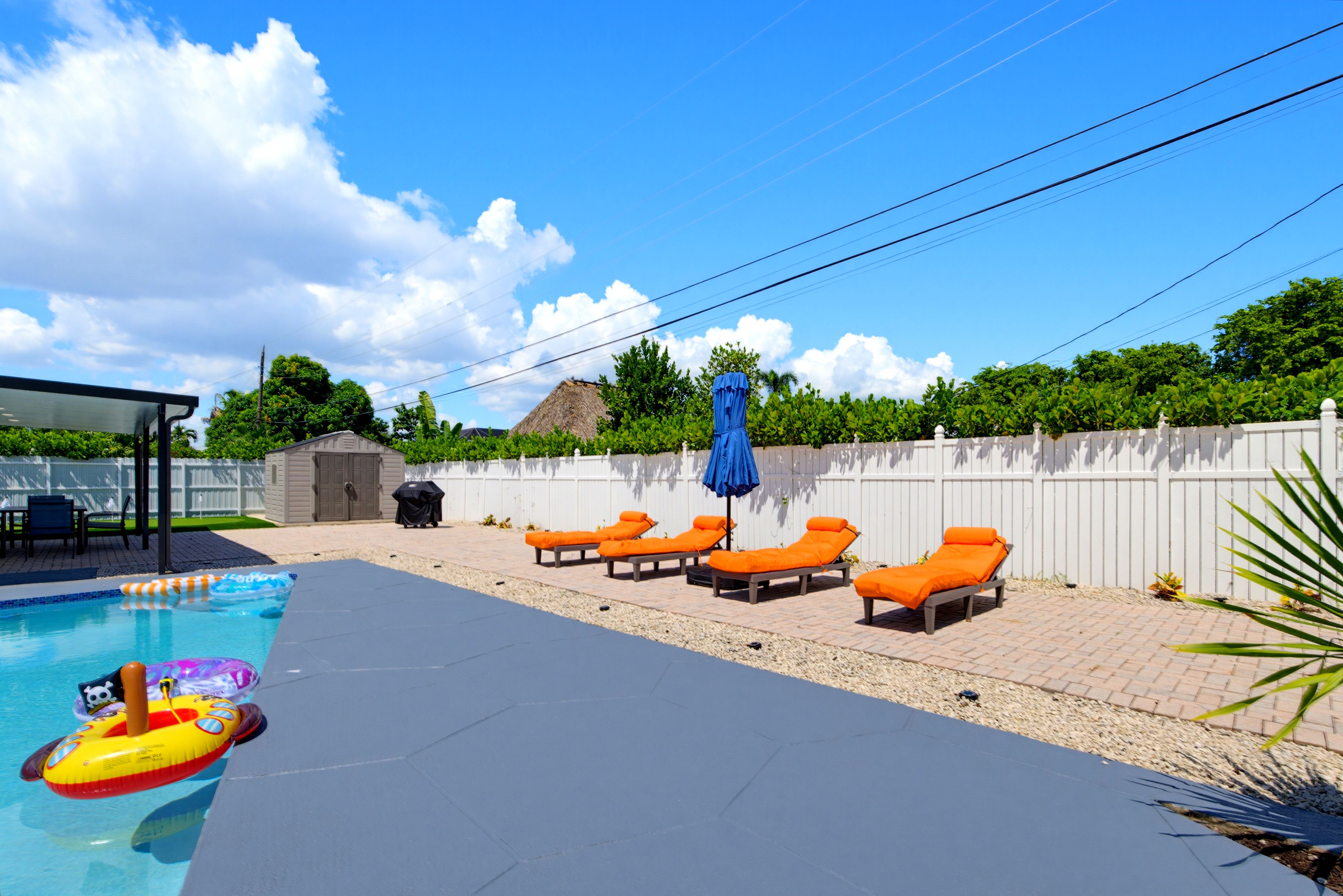 A swimming pool with lounge chairs and a covered barbecue area.