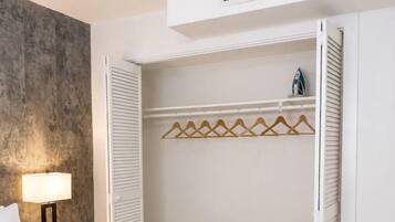 Une chambre d’hôtel avec un lit, une table de chevet, une lampe, une armoire avec une tringle pour suspendre les vêtements et une serviette sur le lit.