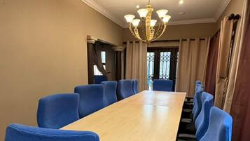 Una sala conferenze con un lungo tavolo, sedie blu, un lampadario e vista dalla finestra.