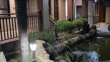 Spazio esterno ben illuminato con fontana, area salotto e un edificio con balcone.