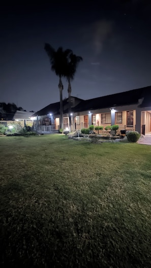 A residential building with a well-maintained lawn, a small water feature, and a porch area. - Host Hub Guest House -Glen marais  (Kempton Park)
