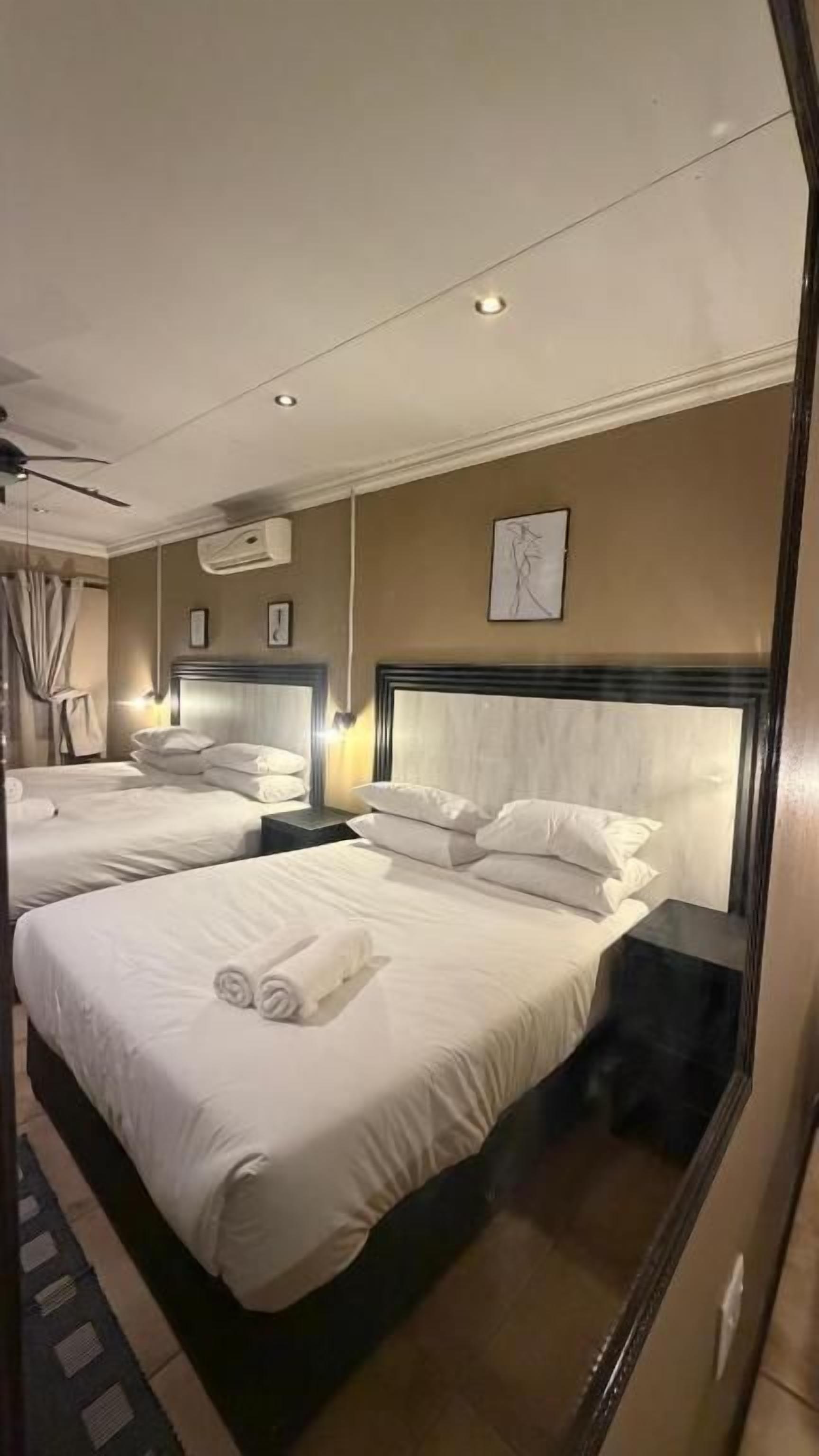 Habitación de hotel con dos camas, un espejo grande y un ventilador de techo.