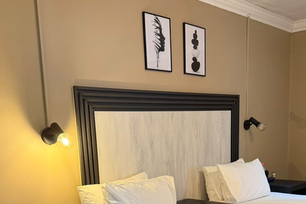 Una habitación de hotel con una cama grande, dos mesitas de noche y dos lámparas de pared.