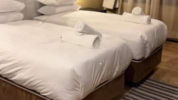 Una camera d'albergo con un letto grande, una testiera, una finestra con tende e un tappeto a righe.