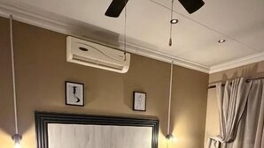 Une chambre d’hôtel avec un grand lit, un ventilateur de plafond et une table de chevet.