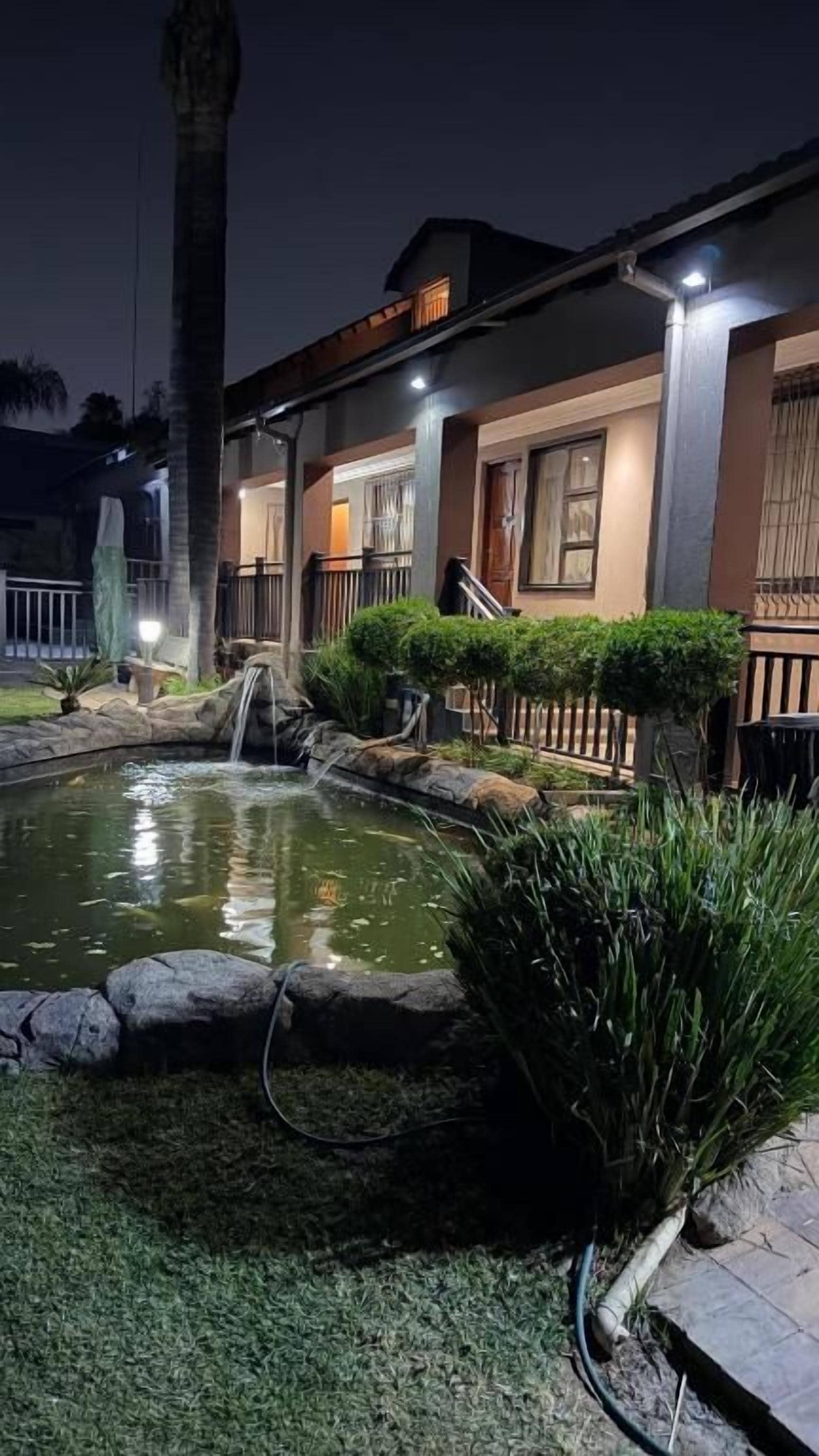 Um imóvel residencial com um pequeno lago, uma cascata e um gramado bem cuidado.