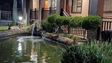 Um imóvel residencial com um pequeno lago, uma cascata e um gramado bem cuidado.