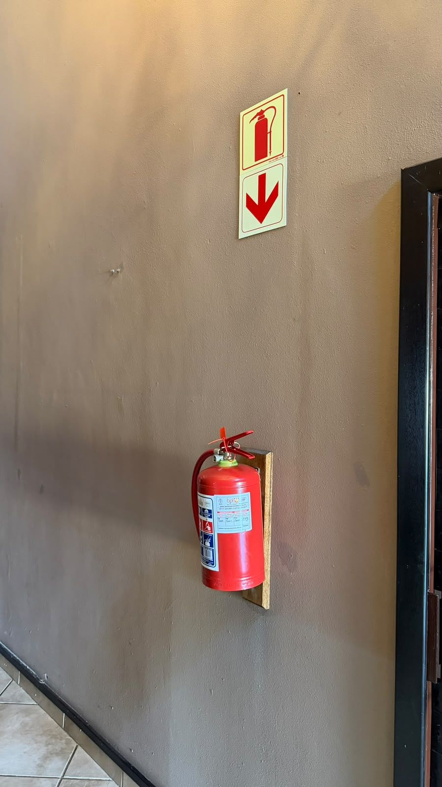Un extintor fijado a la pared con una señal de flecha indicativa encima.