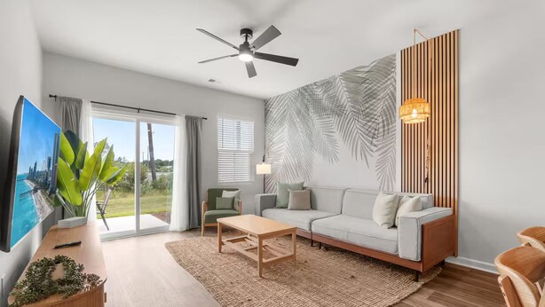 En moderne stue med sofa, sofabord og et stort vindue med udsigt.