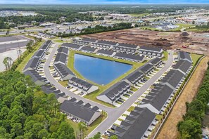 Un vaste complexe résidentiel doté d’un lac central, aménagé selon un plan en forme de grille et comprenant des places de stationnement.