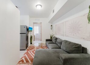 Ein stilvolles Wohnzimmer mit einem grauen Sofa, einem kleinen Couchtisch und einem gemusterten Teppich.