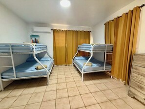 Ein Zimmer mit Etagenbetten, einer Holzkommode und einem Fenster mit Vorhängen.