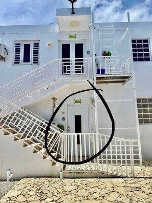 Ein weißes Gebäude mit einer Treppe, die zu einem Balkon führt.