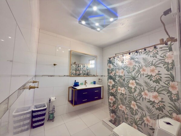 Une salle de bain moderne avec un meuble-lavabo, un miroir et un rideau de douche à motifs floraux.